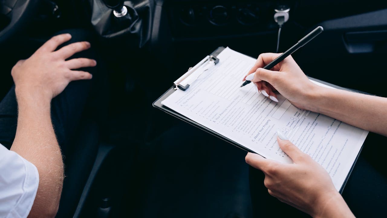 Inspecting a vehicle and noting condition on a clipboard before shipment